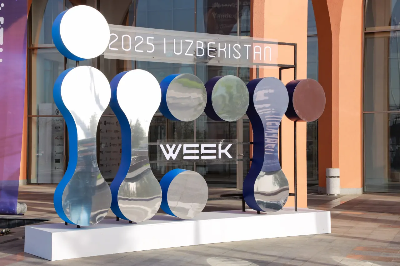 Зеркальная объёмная инсталляция ICT Week 2025 на белом подиуме перед входом в CAEx.