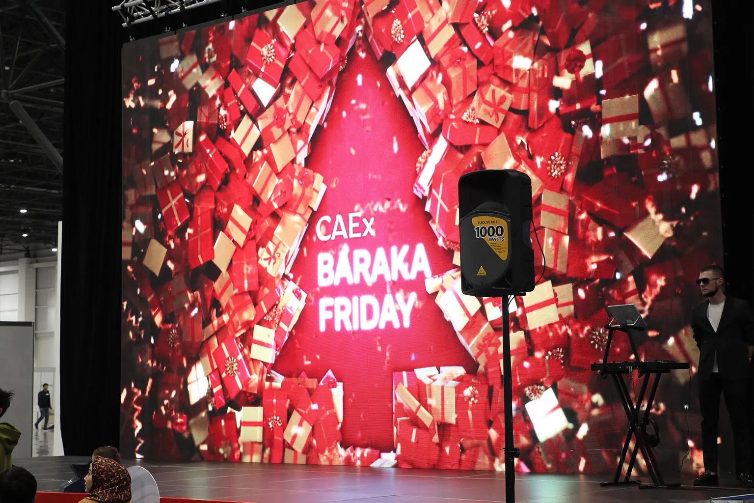 Крупный LED-экран с красной графикой CAEx Baraka Friday и сценическое оборудование в выставочном павильоне.