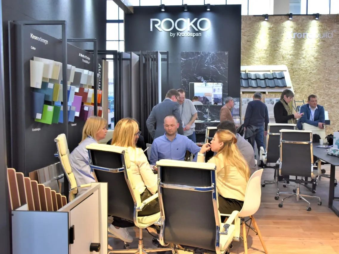 Стенд ROCKO с белой светящейся надписью на тёмной стене, образцами отделочных панелей и зоной переговоров.