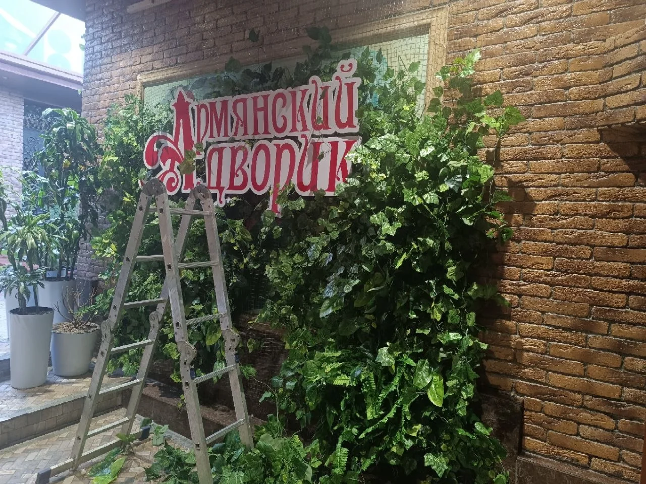 Красно-белые объёмные буквы Армянский дворик на декоративной зелёной стене