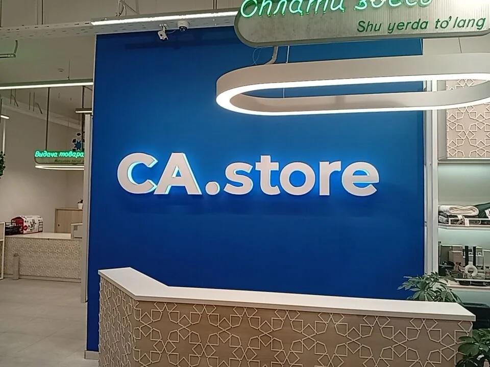 Белые объёмные буквы CA.store на синей стене за стойкой магазина