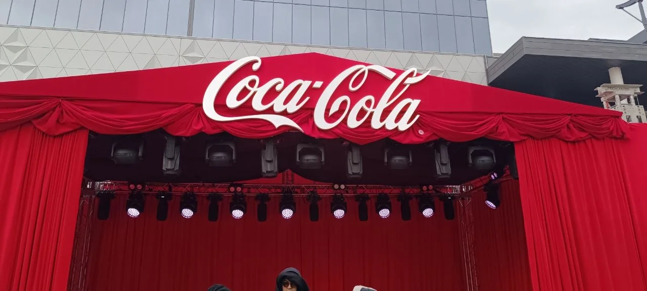 Объёмный белый логотип Coca-Cola на красном портале сцены